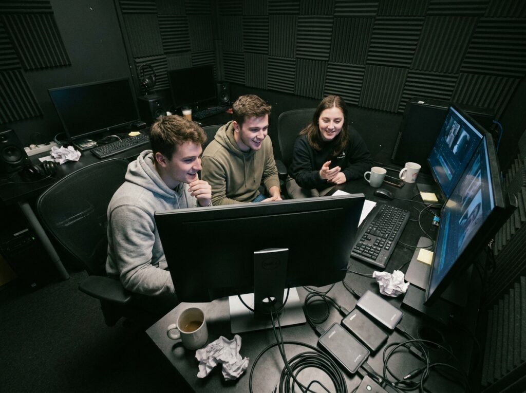 Étudiants en audiovisuel collaborant dans une salle de montage vidéo professionnelle
